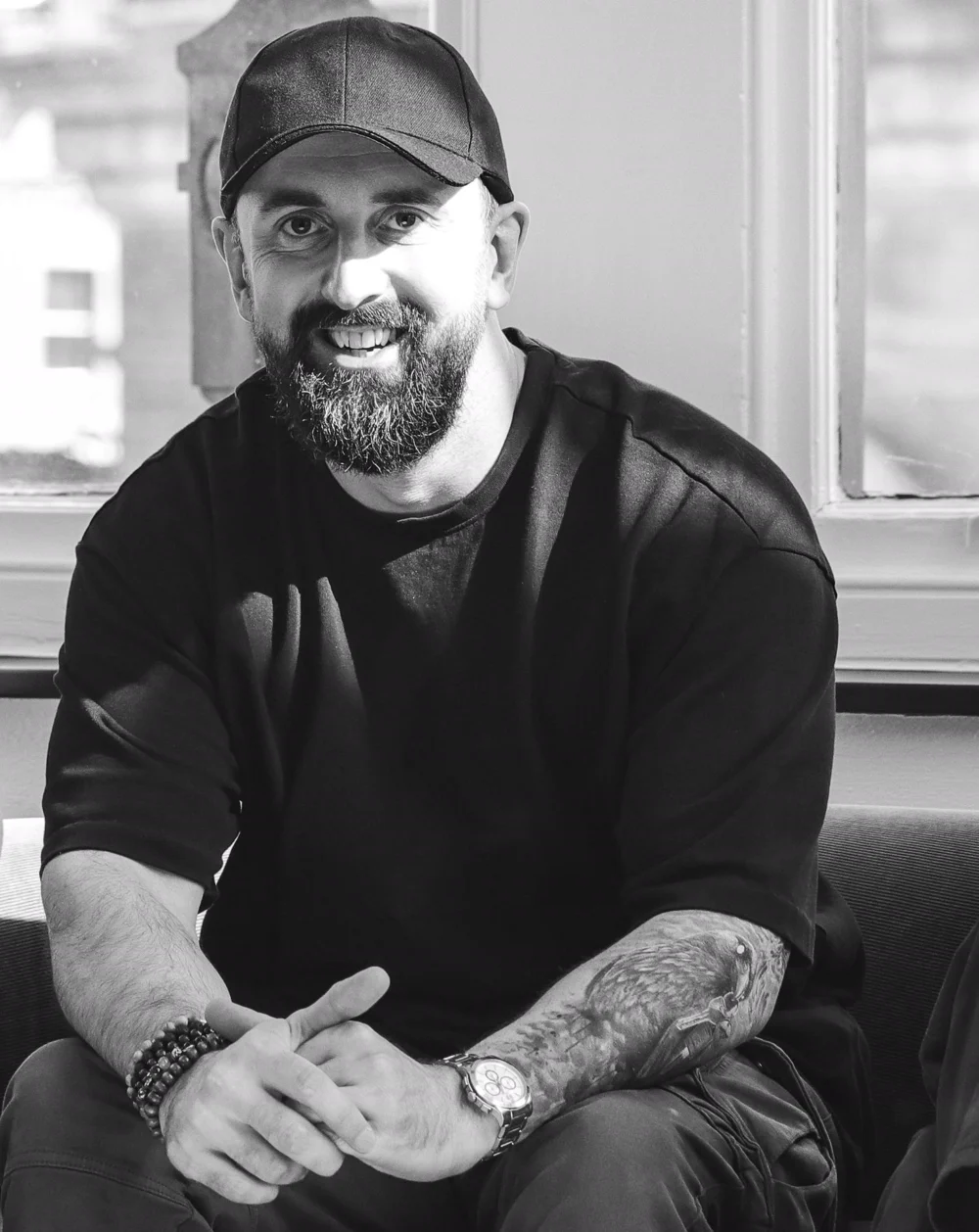 Rob Philbin, in a cap and a black t-shirt, sitting by a window