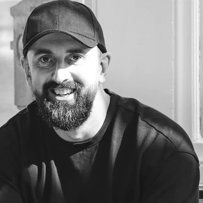 Rob Philbin, in a cap and a black t-shirt, sitting by a window