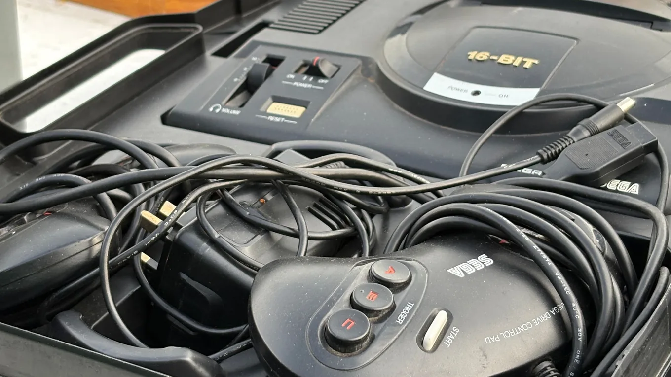 A Sega Mega Drive console and control pad packed into a black carry case with tangled cables